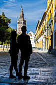 Junges Paar bewundert den Giralda-Turm vom Patio de Banderas-Platz aus, Sevilla, Spanien