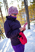 Junge attraktive Frau benutzt ein Mobiltelefon im Skigebiet Pyha, Lappland