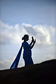 Junge Frau in einer Gruppe von blau gekleideten Studenten benutzt ein Mobiltelefon während eines Besuchs des UNESCO-Weltkulturerbes, Galle Fort, am Binara Full Moon Poya Day