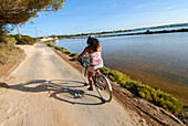 Junge Frau fährt mit dem Fahrrad auf Formentera, Balearen, Spanien