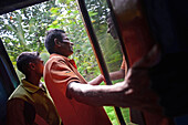 Train travelers looking out the open door in motion, Sri Lanka