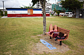 Junge Frau ruht sich auf einer hölzernen Parkbank aus, Ishigaki, Okinawa, Japan