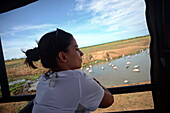 Young woman in safari jeep watching painted storks (Mycteria leucocephala) in the water. Udawalawe National Park, on the boundary of Sabaragamuwa and Uva Provinces, in Sri Lanka.