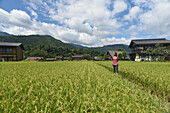 Porträt einer jungen kaukasischen Frau im Freien in Shirakawa-go, einem traditionellen Dorf, das einen als gassho-zukuri bekannten Baustil zeigt, Präfektur Gifu, Japan