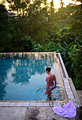 Young attractive woman enters an infinity edge swimming pool at The Dutch House, Galle, Sri Lanka