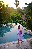 Young attractive woman enters an infinity edge swimming pool at The Dutch House, Galle, Sri Lanka