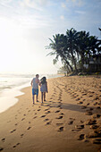 Couple walking on Hikkaduwa beach at sunset, Sri Lanka