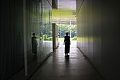 Silhouette of young woman walking in corridor, view from behind.
