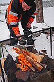 Antti, junger Reiseleiter von VisitInari, bereitet Kaffee und Tee auf einem Feuer in der Wildnis des Inari-Sees, Lappland, Finnland, zu