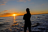 Silhouette einer jungen Frau, die einen wunderschönen Sonnenuntergang am Strand von Migjorn, Formentera, Spanien, genießt