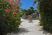 Junge Frau fährt Fahrrad auf der Insel Taketomi, Präfektur Okinawa, Japan