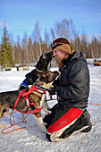Eine Gruppe schöner Hunde küsst einen jungen Mann. Wildnis-Husky-Schlittentour in der Taiga mit Bearhillhusky in Rovaniemi, Lappland, Finnland