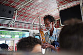 Ambulant musician playing tambourine inside a bus, Sri Lanka