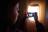 Young woman takes a photo through window during flight