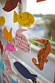 Fish shaped notes, made by kids, decorate the glass windows at Taketomi port, Okinawa, Japan