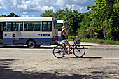Frau fährt Fahrrad auf der Insel Taketomi, Präfektur Okinawa, Japan