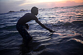 Ein junger Einheimischer, der durch den Tsunami viel verloren hat, füttert die Schildkröten am Strand von Hikkaduwa, Sri Lanka