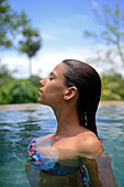 Young attractive woman enjoying a bath in the infinity edge swimming pool at The Dutch House, Galle, Sri Lanka