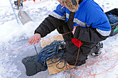 Fisherman practicing ice fishing in Lake Inari, Lapland, Finland