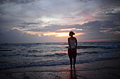 Junge Frau genießt den Sonnenuntergang am Strand von Hikkaduwa, Sri Lanka