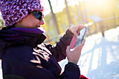Junge attraktive Frau benutzt ein Mobiltelefon im Skigebiet Pyha, Lappland