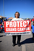 Frau hält Protect Grand Canyon"-Schild während der morgendlichen Parade auf der Navajo Nation Fair, einer weltbekannten Veranstaltung, die die Landwirtschaft, die Kunst und das Kunsthandwerk der Navajo präsentiert und durch kulturelle Unterhaltung das Erbe der Navajo fördert und bewahrt. Window Rock, Arizona"