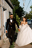 Bride and groom walking on sidewalk in town
