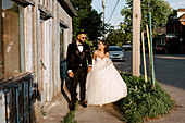 Bride and groom walking on sidewalk in town