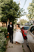Bride and groom walking on sidewalk