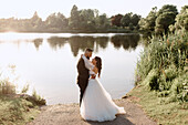 Bride and groom embracing on lakeshore