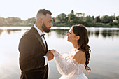 Bride and groom holding hands on lakeshore