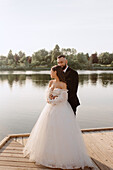 Bride and groom embracing on lakeshore