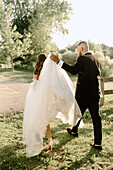 Rear view of bride and groom walking in park