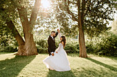 Braut und Bräutigam halten sich im Park an den Händen
