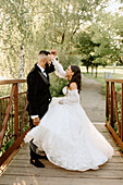 Bride and groom on footbridge in park