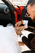 Close-up of groom fastening brides shoe in car