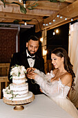 Smiling bride and groom cutting wedding cake