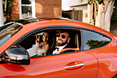 Lächelnde Braut und Bräutigam in rotem Auto