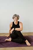 Portrait of smiling woman sitting on exercise mat