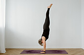 Frau macht Handstand im Zimmer