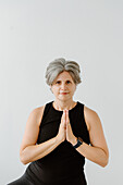 Studio shot of smiling woman with hands clasped