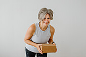 Porträt einer lächelnden Frau, die einen Yogablock hält