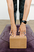 Nahaufnahme einer Frau, die Yoga mit einem Yogablock auf einer Übungsmatte übt