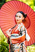 Portrait of woman in kimono holding red parasol