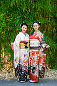 Portrait of two women wearing kimonos in park
