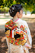 Rückansicht einer Kimono tragenden Frau im Park