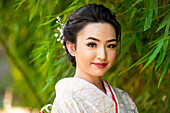 Porträt einer lächelnden Frau in Kimono im Park