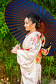 Nachdenkliche Frau mit Kimono und Sonnenschirm in der Hand