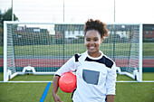 UK, Portrait of smiling female soccer player (12-13) in front of goal