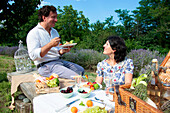 Smiling mature couple enjoying picnic in lavender field